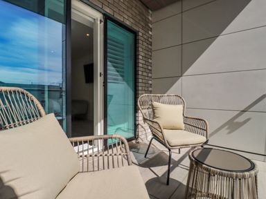 An outdoor patio with two wicker chairs with cushions and a small round table at 30 Cliff Edge in Newquay