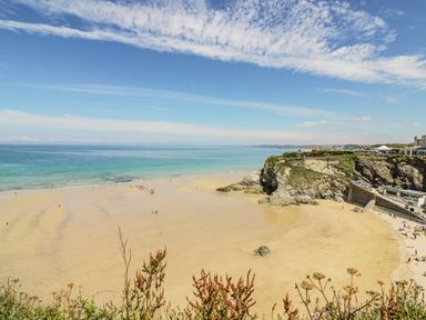 A sandy beach with people near the water and cliffs on the right side at 30 Cliff Edge in Newquay