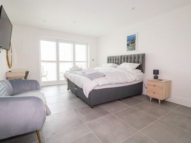 A bedroom with a bed a sofa a nightstand with a lamp and a desk at 30 Cliff Edge in Newquay