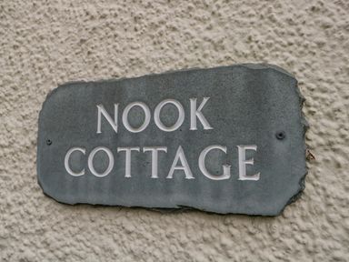 A stone sign with the text Nook Cottage on a textured wall at Nook Cottage in Rosthwaite near Keswick