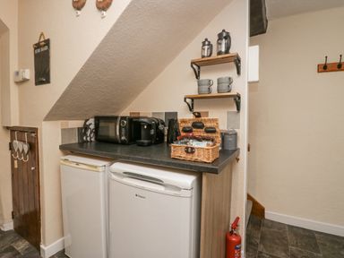 A small kitchen area with two white refrigerators a microwave coffee machine and a wicker basket on the counter at Nook Cottage in Rosthwaite near Keswick