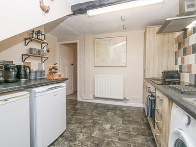 A kitchen with appliances shelves and a map on the wall at Nook Cottage in Rosthwaite near Keswick