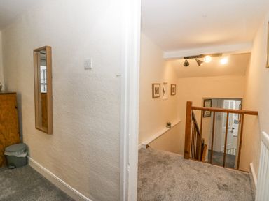 A staircase with wooden railing and framed pictures on the wall at Nook Cottage in Rosthwaite near Keswick