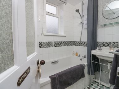 A bathroom with a bathtub shower sink and a towel hanging on the bathtub at Nook Cottage in Rosthwaite near Keswick