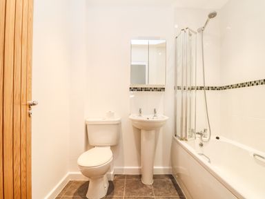 A bathroom with a toilet sink mirror and bathtub with shower at 11 Towan Valley in Porthtowan
