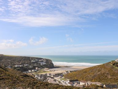 A coastal village with houses on hills overlooking a sandy beach and the ocean at 11 Towan Valley in Porthtowan