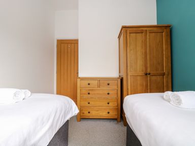 A bedroom with two beds a wooden chest of drawers and a wooden wardrobe at 11 Towan Valley in Porthtowan