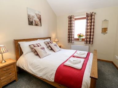A bedroom with a wooden bed and bedside tables with lamps at Summerseat in Kirkby Stephen