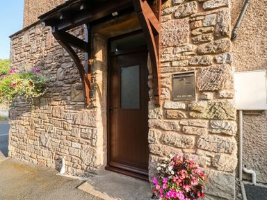 An entrance with a wooden door and stone wall at Summerseat in Kirkby Stephen