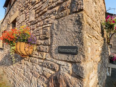 A flower basket and nameplate on a stone wall at Summerseat in Kirkby Stephen