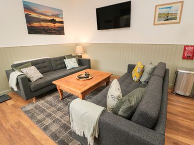 A living room with two grey sofas a wooden coffee table and a wall-mounted TV at The Bakery in Middleton near Belford