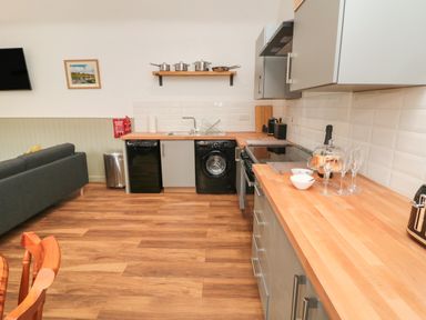 A kitchen with wooden countertops black appliances and a grey sofa at The Bakery in Middleton near Belford