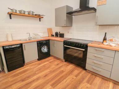 A kitchen with wooden floor gray cabinets black appliances and cooking utensils on a shelf at The Bakery in Middleton near Belford