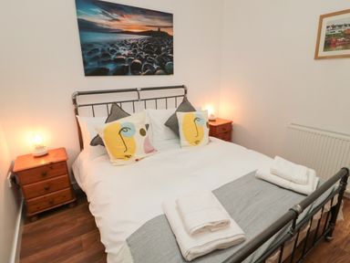A bedroom with a double bed with patterned pillows and folded towels on a blanket at The Bakery in Middleton near Belford