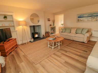 A living room with two sofas a wooden coffee table a fireplace a TV on a wooden stand and a standing lamp at 46 Castle Street Norham