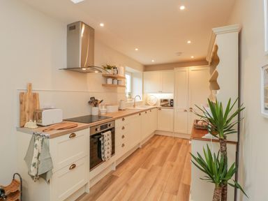 A kitchen with white cabinets wooden countertops and plants at 46 Castle Street Norham