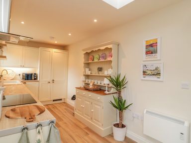 A kitchen with white cabinets wooden countertops a hutch with dishes a potted plant and framed pictures at 46 Castle Street in Norham