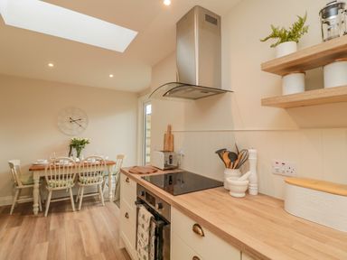 A kitchen with wooden countertops a stove and utensils next to a dining table with chairs at 46 Castle Street Norham