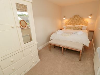 A bedroom with a bed with a patterned headboard and bench at 46 Castle Street in Norham