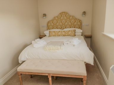A bedroom with a bed with patterned headboard and folded towels at 46 Castle Street in Norham