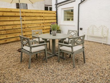 An outdoor patio area with a round table and four chairs on a gravel ground at 46 Castle Street Norham