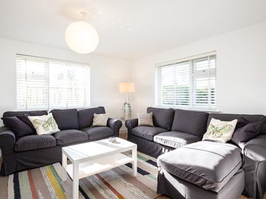 A living room with two dark sofas a white coffee table a floor lamp and striped rug at Obos Retreat in St Minver near Rock