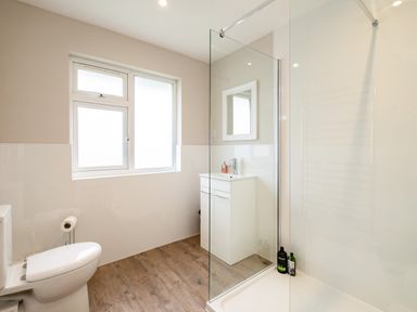 A bathroom with a toilet sink vanity unit shower with glass partition and frosted window at Obos Retreat in St Minver near Rock