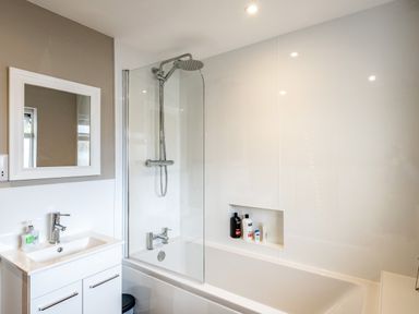 A bathroom with a bathtub shower combination a sink with faucet and a mirror at Obos Retreat in St Minver near Rock