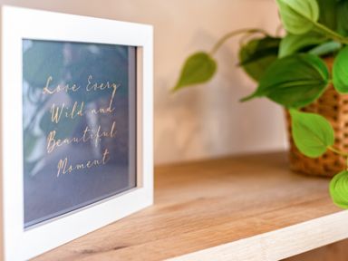 A framed quote on a wooden surface next to a potted plant with green leaves at Obos Retreat in St Minver near Rock