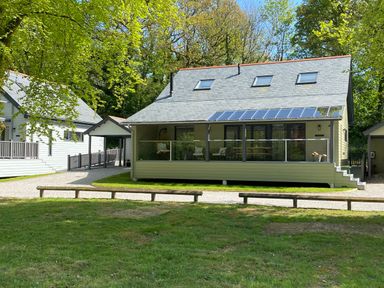 A green house with a glass balcony in a wooded area at Primrose Hellandbridge near Bodmin