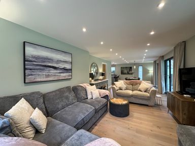 A living room with grey sofas wooden floor and painting on the wall at Primrose in Hellandbridge near Bodmin
