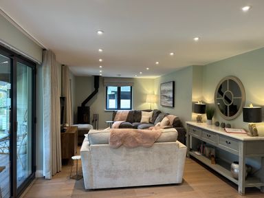 A living room with two sofas a wood burning stove and a console table with lamps and a mirror at Primrose Hellandbridge near Bodmin