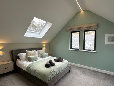 A bedroom with a bed under a skylight and two windows at Primrose in Hellandbridge near Bodmin