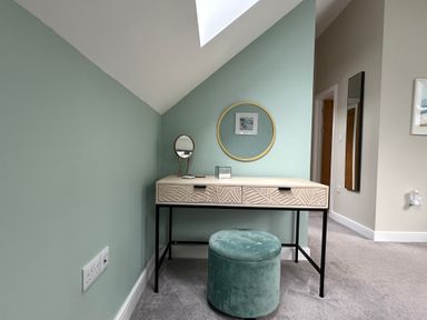 A vanity table with a round mirror a small table mirror a decorative box and a cushioned stool in a room at Primrose in Hellandbridge near Bodmin