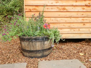 A wooden planter with various flowers and plants outside a wooden building at Hideaway Cabin in Cadbury near Thorverton