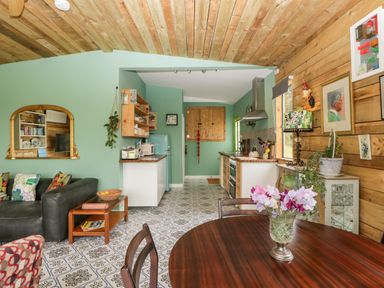 A kitchen and dining area with wooden ceiling and patterned floor at Lulu Logs in Congresbury