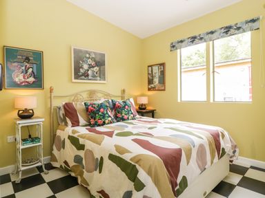 A bedroom with a double bed two bedside tables with lamps and framed pictures on the walls at Lulu Logs in Congresbury