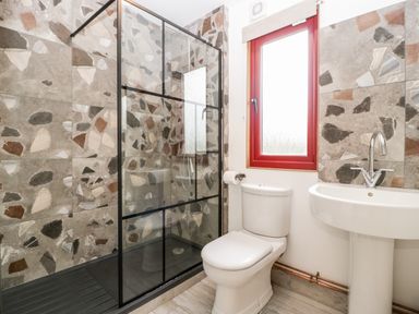 A bathroom with a shower, toilet, sink, and a window at Down the Rabbit Hole in Brinsea near Congresbury