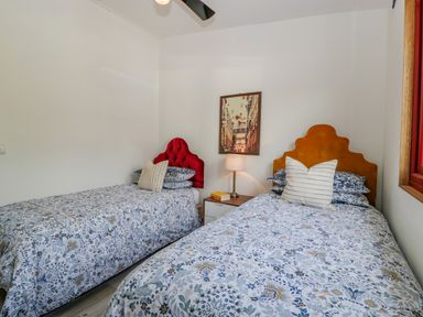 A bedroom with two single beds with patterned bedding a nightstand lamp and framed picture on the wall at Down the Rabbit Hole in Brinsea near Congresbury