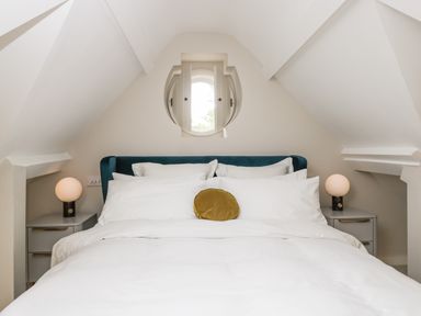 A bedroom with a bed in the center and two bedside tables with lamps by The Hayloft in Sherston