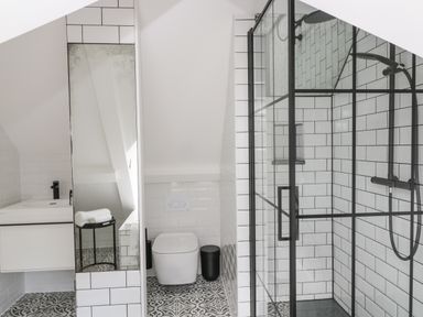 A bathroom with a toilet sink mirror and glass shower enclosure at The Hayloft in Sherston
