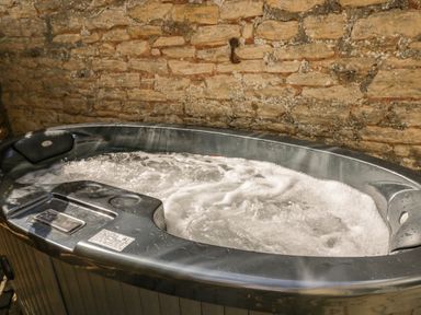 A bubbling hot tub against a stone wall at The Hayloft in Sherston