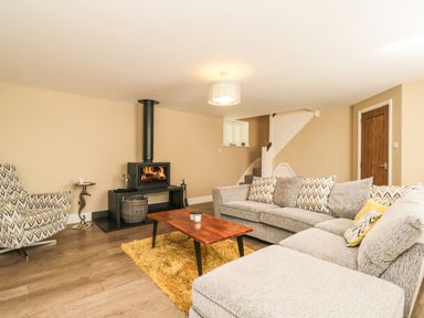 A living room with a fireplace a wooden coffee table and patterned armchair at The Coach House Westonbirt near Tetbury