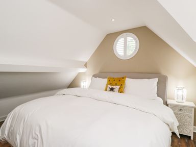 A bedroom with a bed white bedding pillows and bedside tables with lamps at The Coach House in Westonbirt near Tetbury