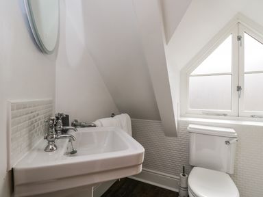 A bathroom with a sink a toilet a round mirror and a window at The Coach House Westonbirt near Tetbury