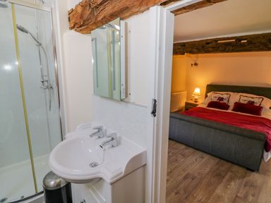 A bathroom with a double sink and shower next to a bedroom with a double bed and lamp at Munderfield Mill in Munderfield near Bishops Frome