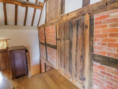 An interior with wooden beams exposed brick walls a wooden door and a wooden cabinet at Munderfield Mill in Munderfield near Bishops Frome
