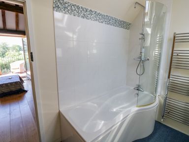 A bathroom with a bathtub and shower next to a heated towel rail at Munderfield Mill in Munderfield near Bishop's Frome