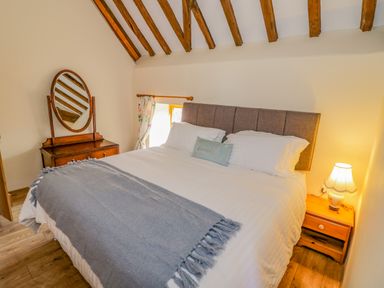 A bedroom with a bed a nightstand with a lamp and a wooden vanity at Munderfield Mill in Munderfield near Bishops Frome
