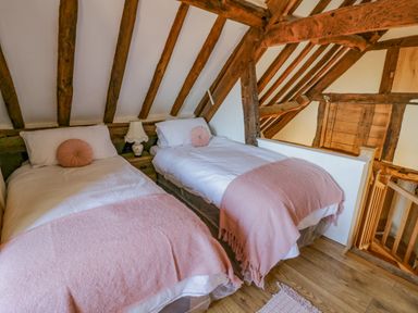 A bedroom with two single beds and wooden beams at Munderfield Mill in Munderfield near Bishops Frome